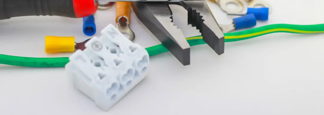 Pliers, crimp terminals and a white connector block beside a green and yellow earth wire.