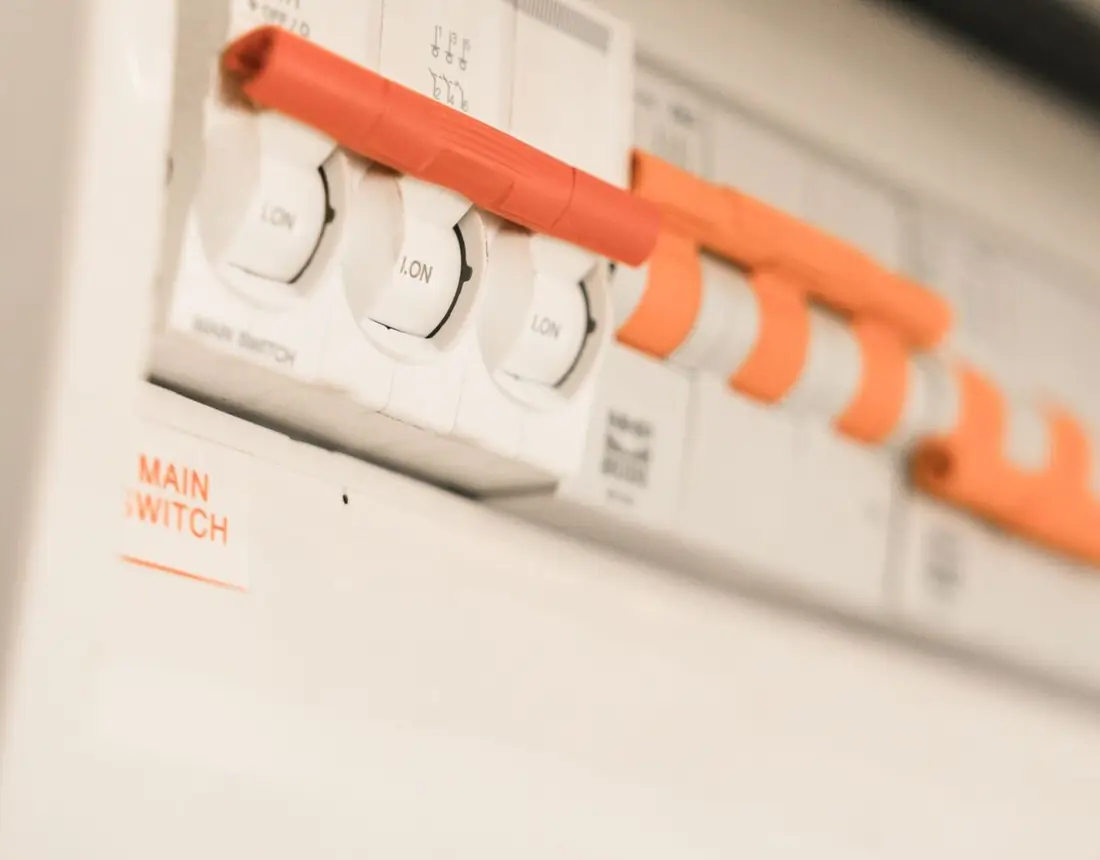 Close-up of a white fuse board with its row of circuit breakers switched on.