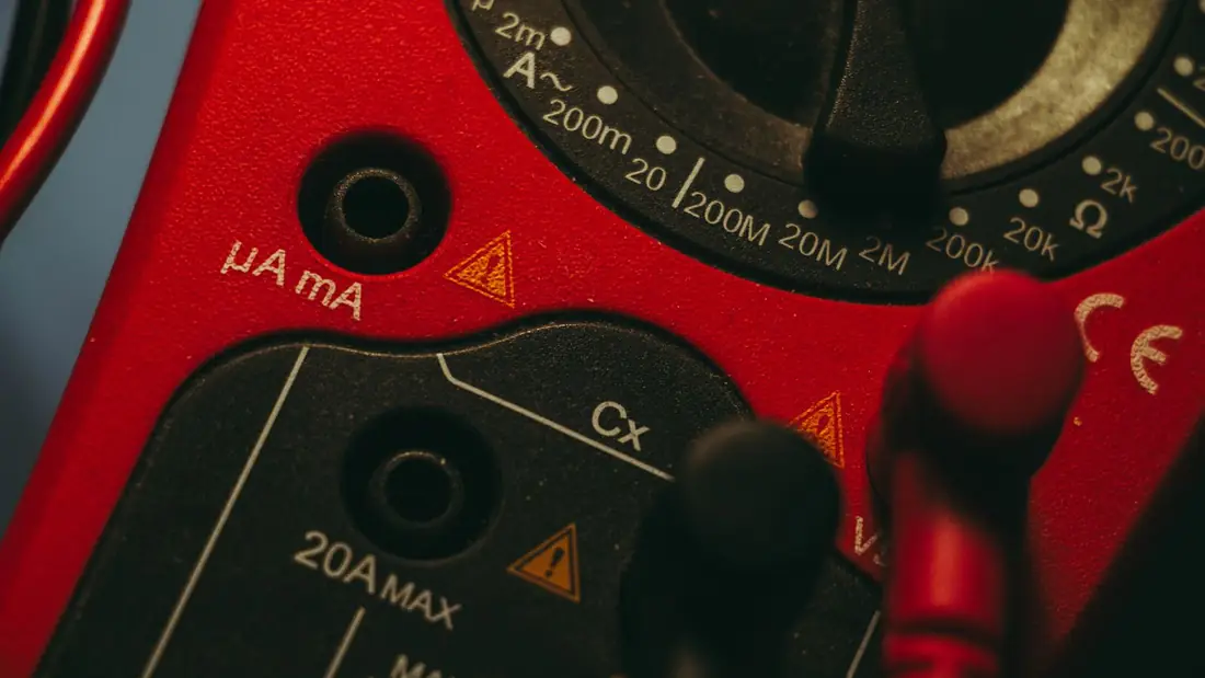 Close-up of a red multimeter dial and its test lead sockets.